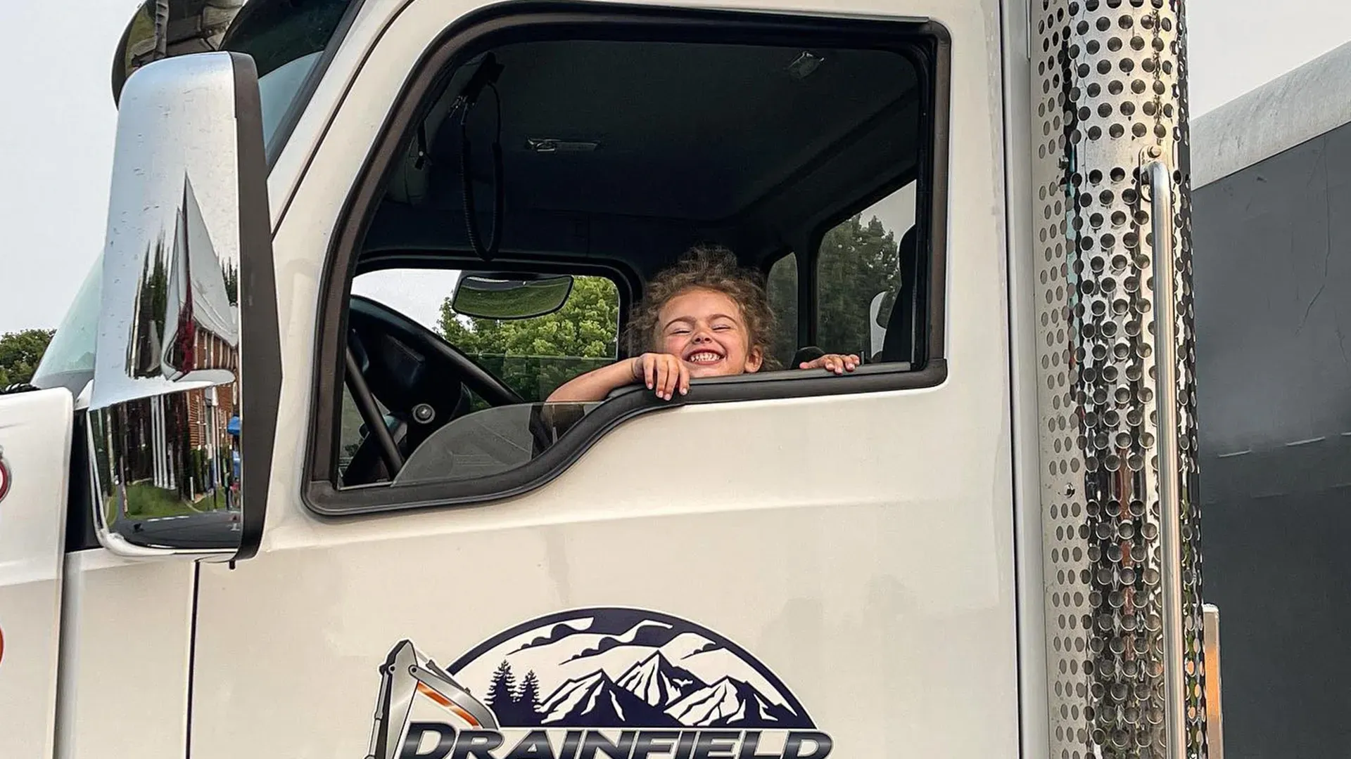 Young girl smiling through the window of Drainfield Solutions truck