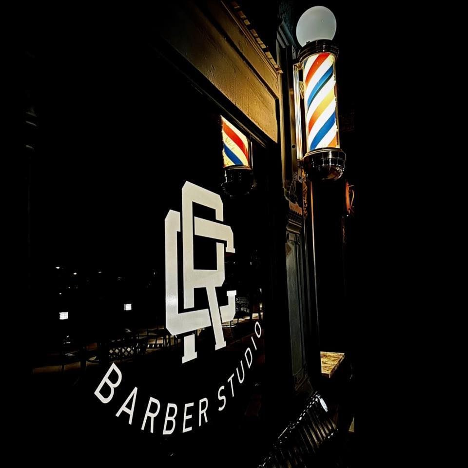 Barber shop window with classic barber pole lit at night in downtown setting