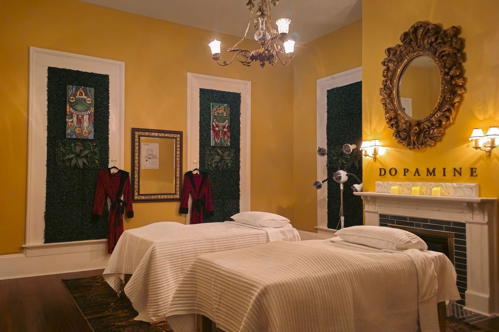 Two massage beds in a luxury yellow spa room with a gold mirror, 