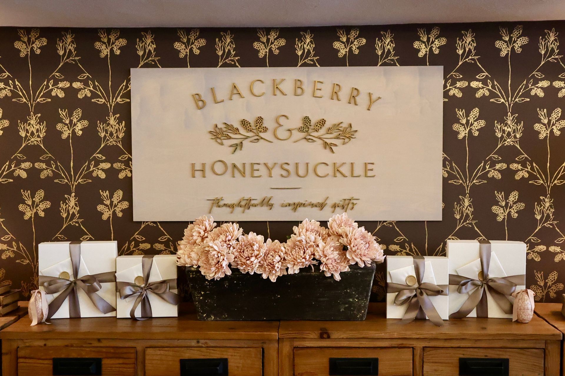 Blackberry Honeysuckle branded sign on wall behind checkout desk and flowers.
