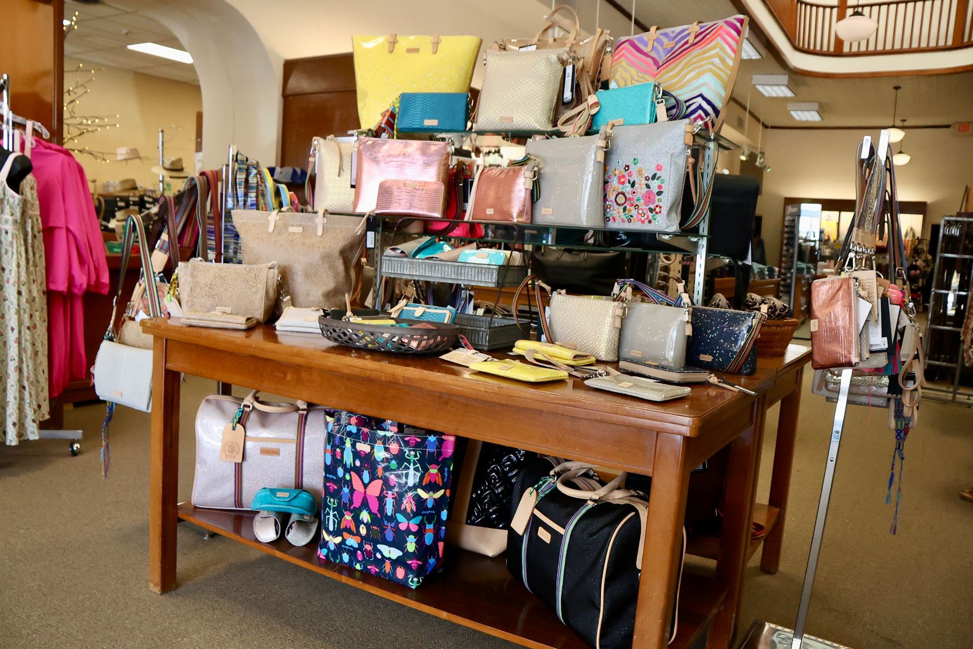 Wooden display table filled with assorted embroidered, patterned, and leather handbags.