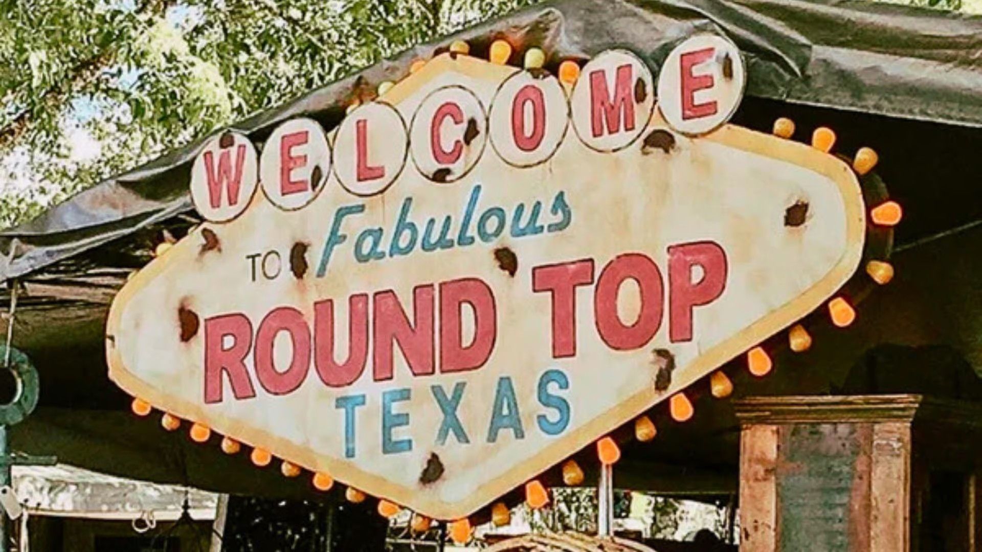 A weathered, diamond-shaped sign with lights reads 