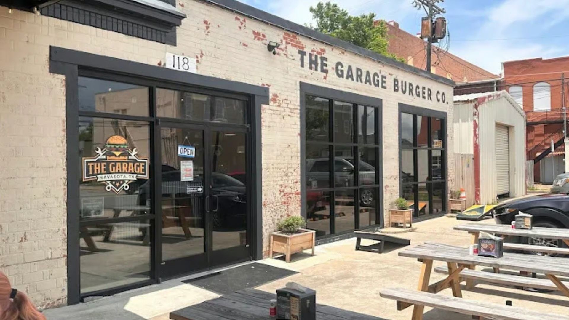 The Garage Burger Co. storefront on a sunny day, with outdoor picnic tables and brick exterior.