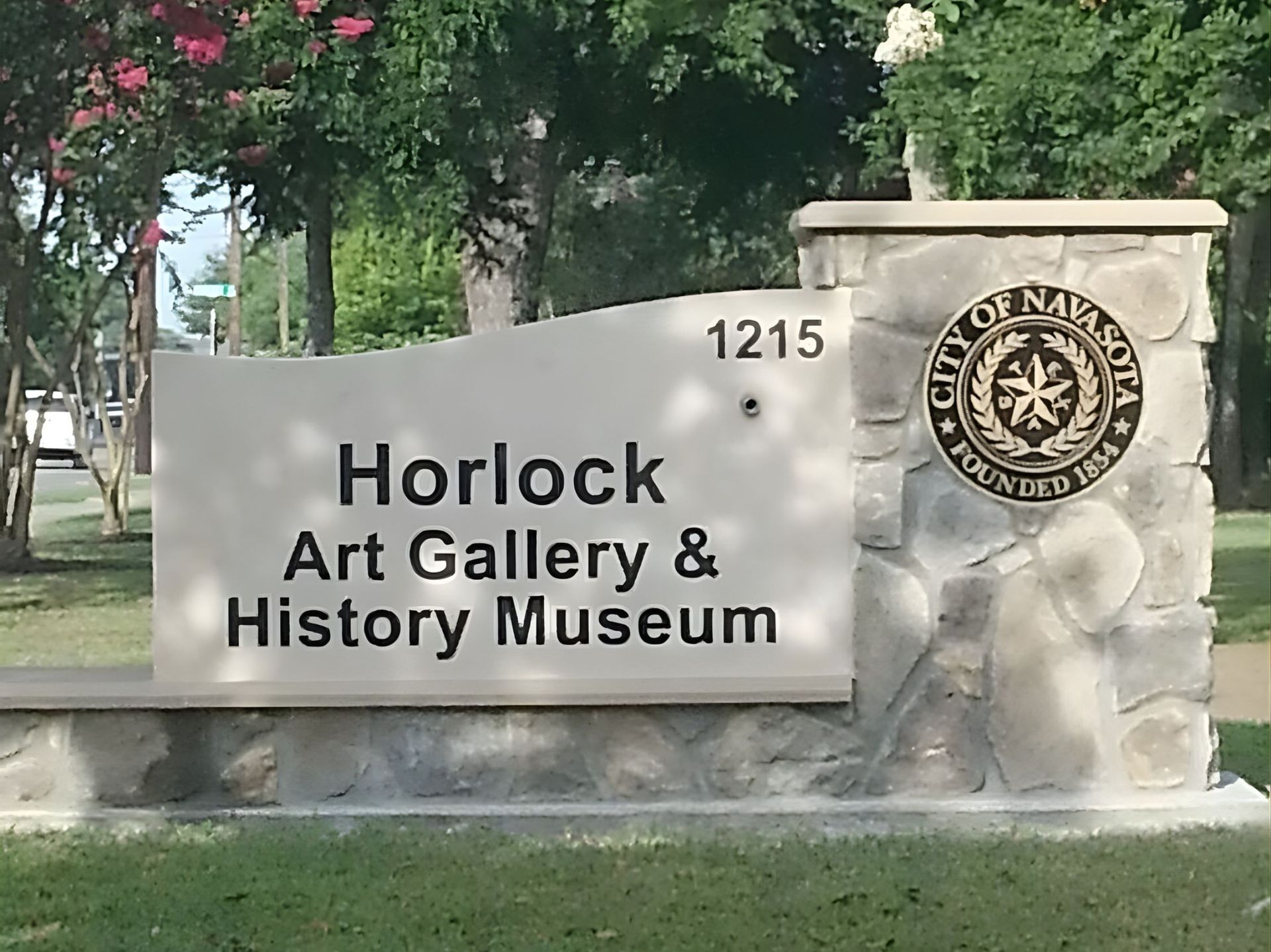 A stone sign for the Horlock Art Gallery & History Museum in Navasota, Texas, featuring the city seal.