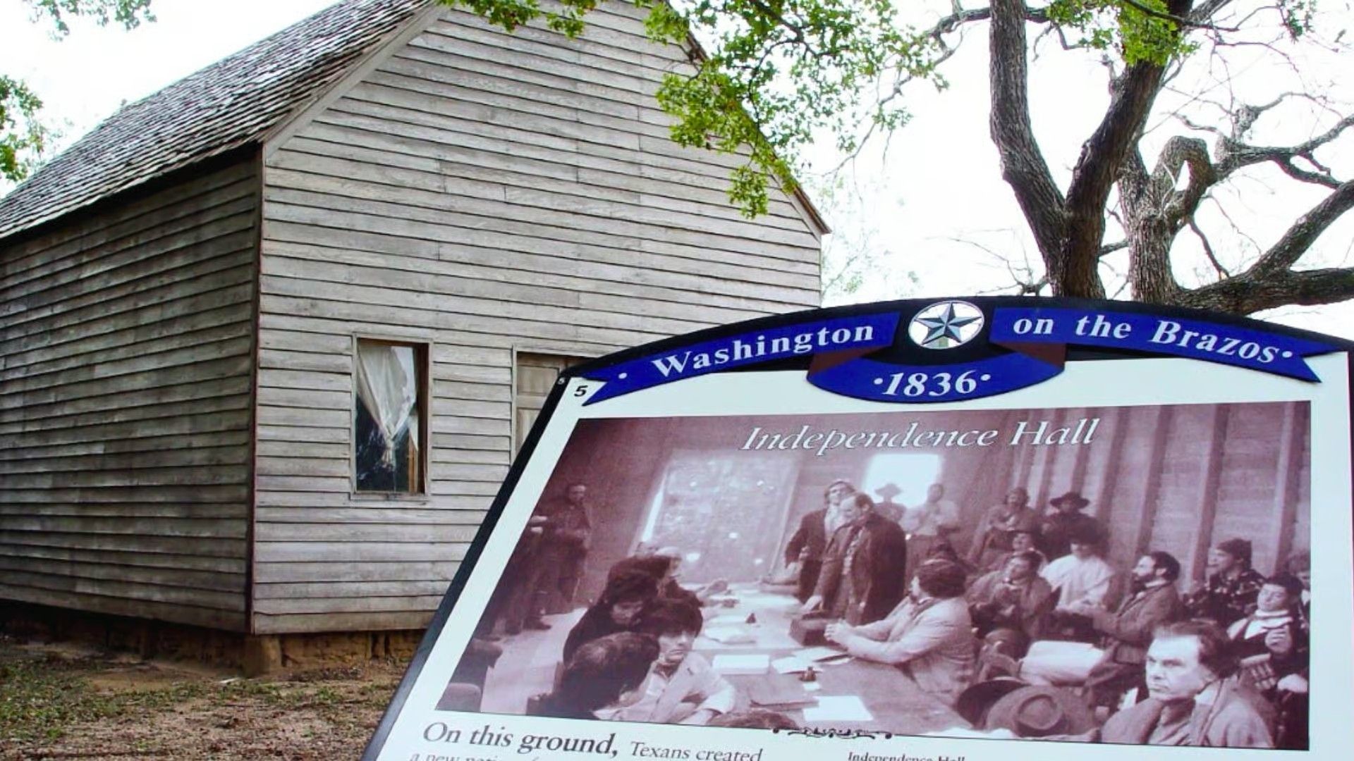 A replica of Independence Hall at Washington-on-the-Brazos with an informational sign about the 1836 Texas convention.