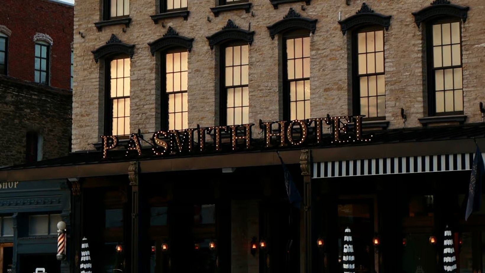 A historic brick building labeled P.A. Smith Hotel with lit windows and a striped awning at the entrance.