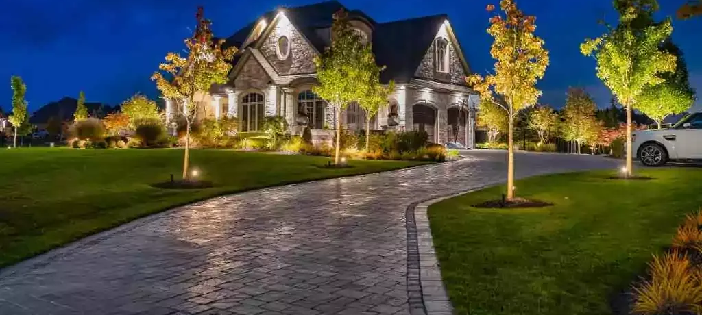 Three pots filled with yellow and red flowers are sitting on a gravel sidewalk.