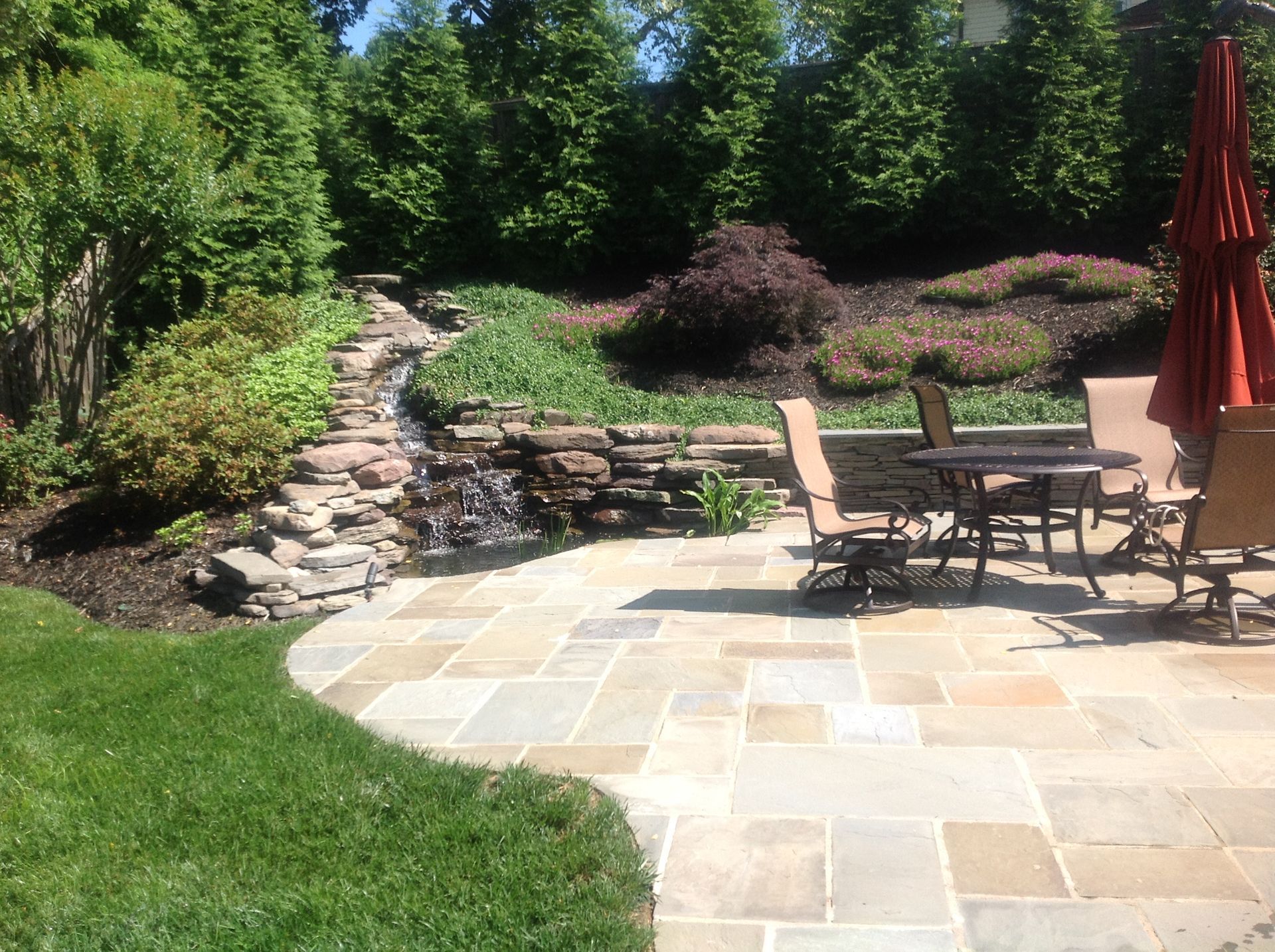 A patio with a table and chairs and a waterfall in the background.