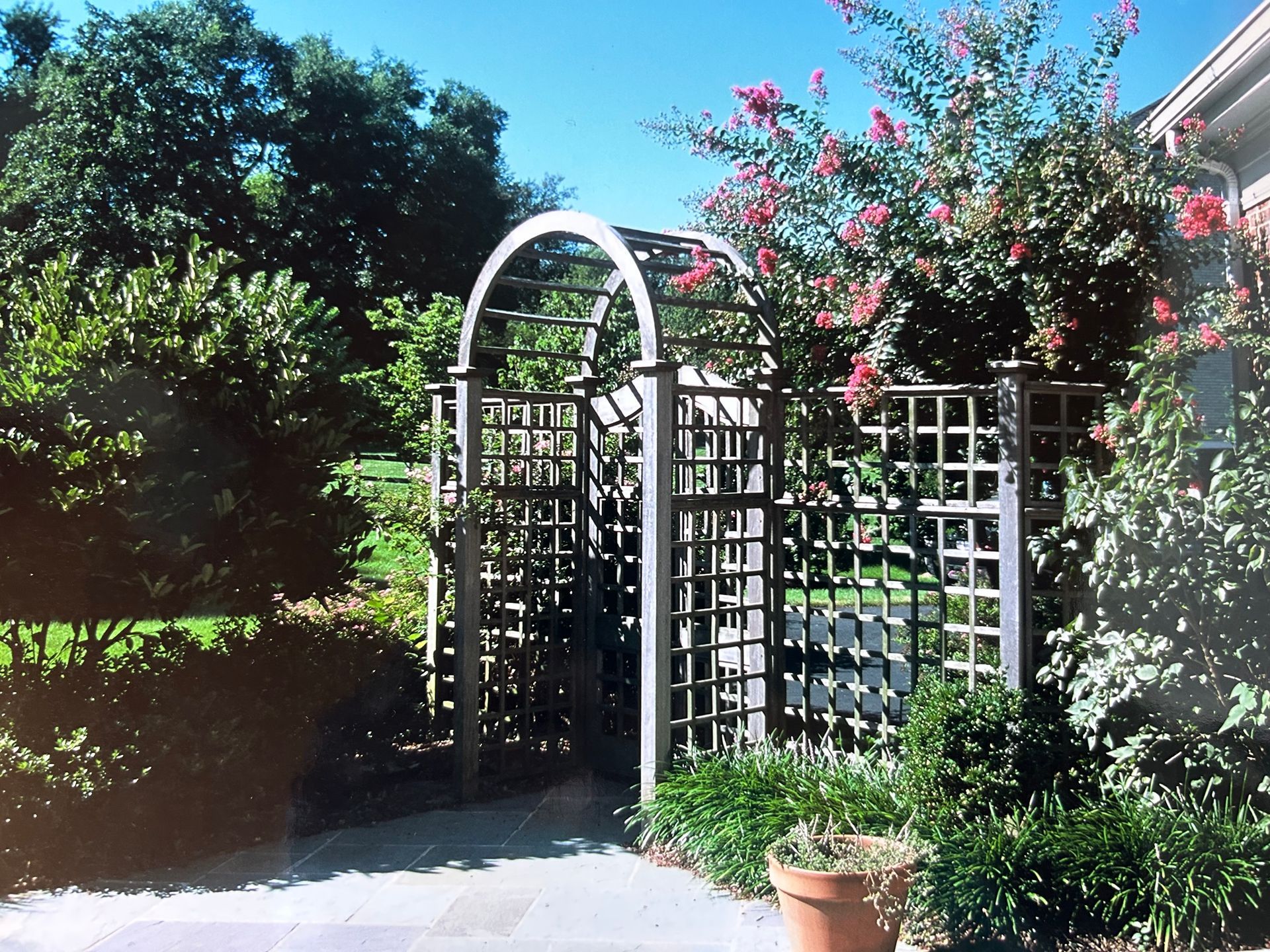 A garden with a fence and a gate leading to a house
