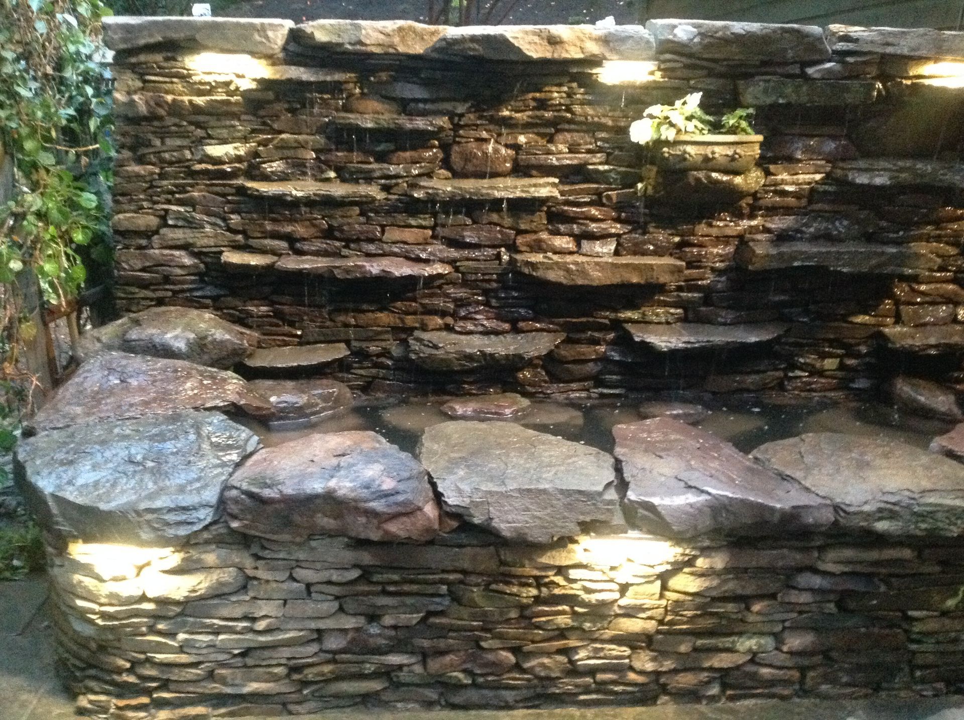 A stone wall with a waterfall in the middle of it