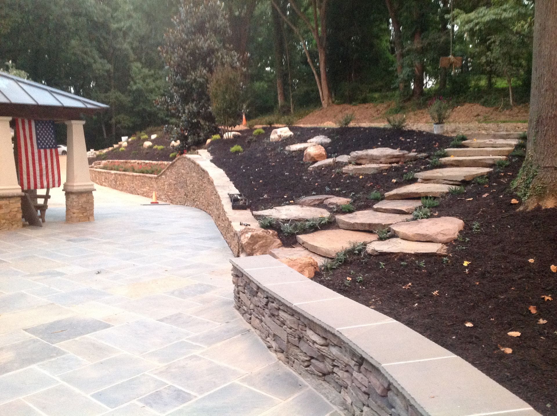 A stone walkway leading to a gazebo with an american flag in the background