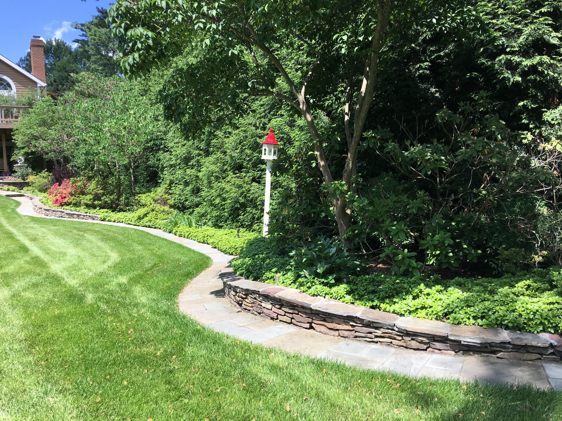 A lush green lawn with a stone walkway leading to a house.