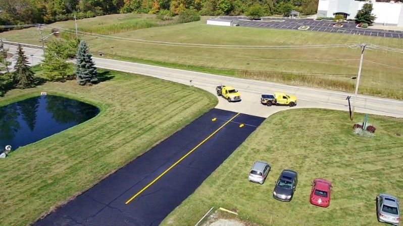 Sealcoat application on road in Fort Wayne, IN. You can see Midwest Seal Team workers applying sealcoat to a road in Fort Wayne, IN, as part of routine maintenance to prolong its lifespan.
