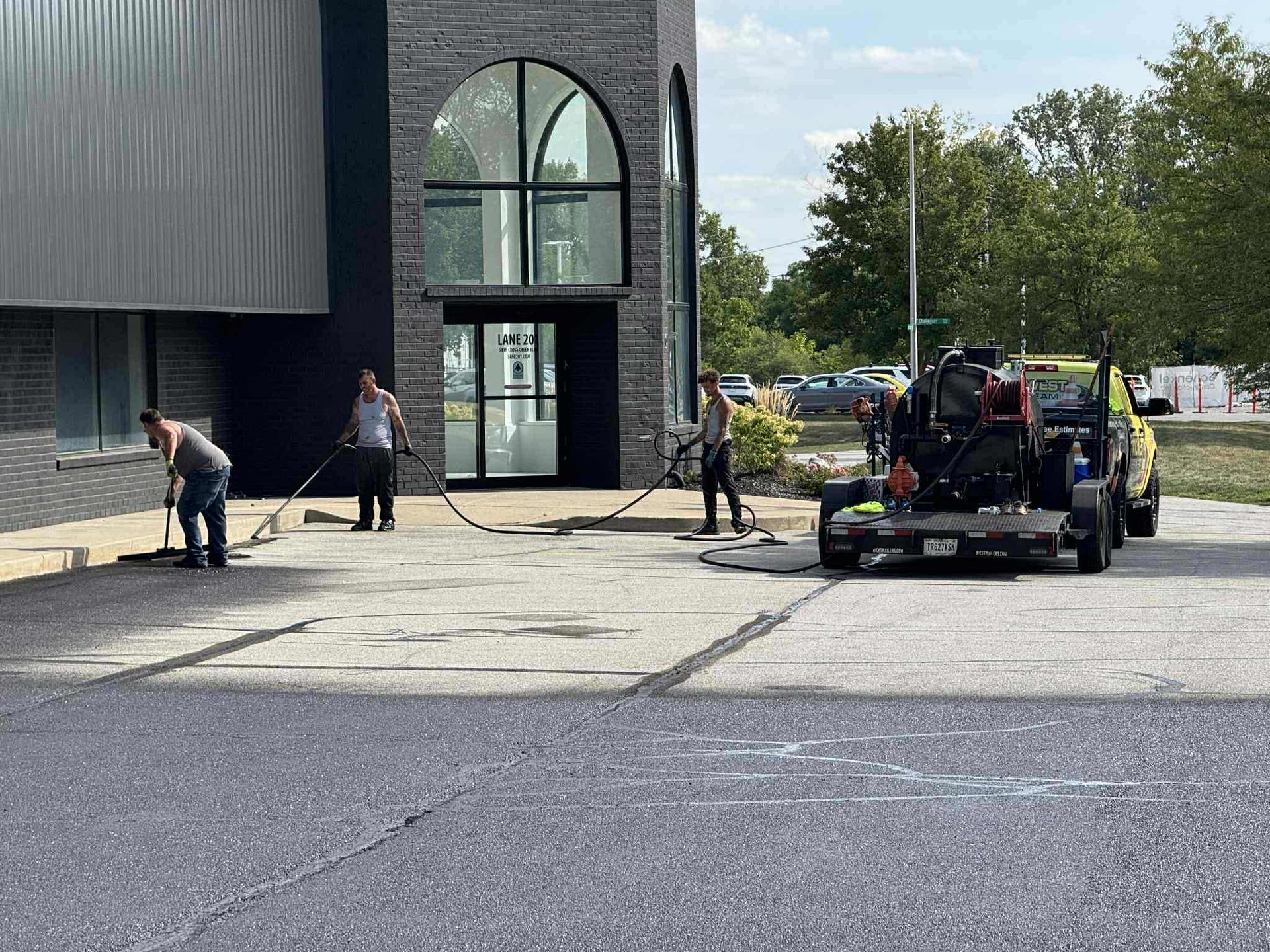 Image of Midwest Seal Team Sealcoating a parking lot in Fort Wayne, IN. You can see the Midwest Seal Team crew working on sealcoating the edges of the parking area. 