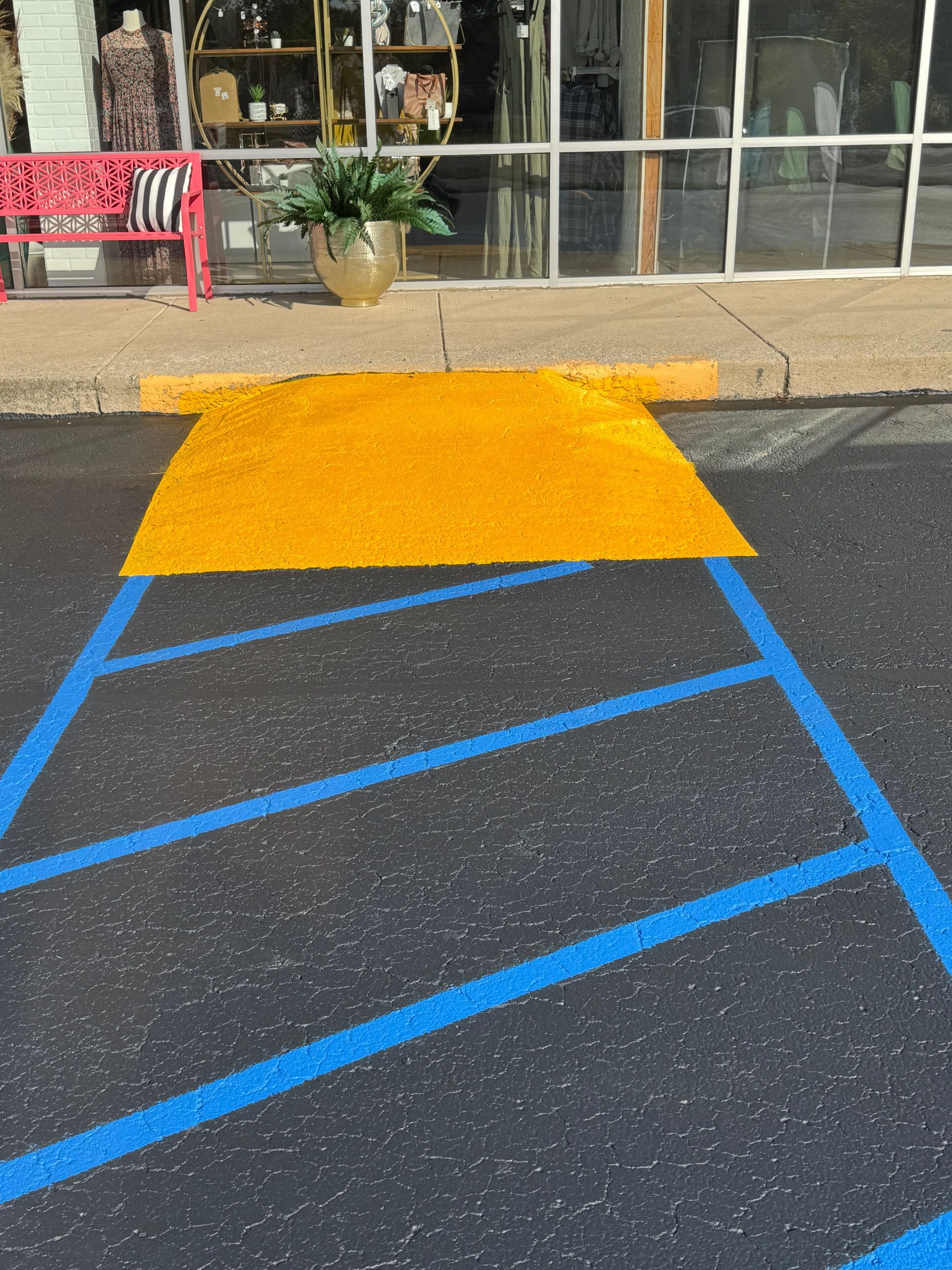 Image showing a parking space that was painted by Midwest Seal Team. You can see a blue crosswalk and a yellow handicap ramp.
