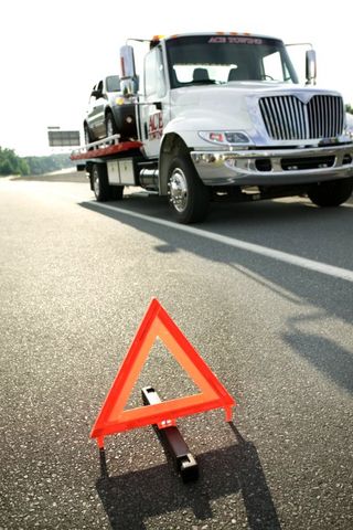 Safety triangle and tow truck on highway - Towing Services and Auto Repair in Hinckley, MN