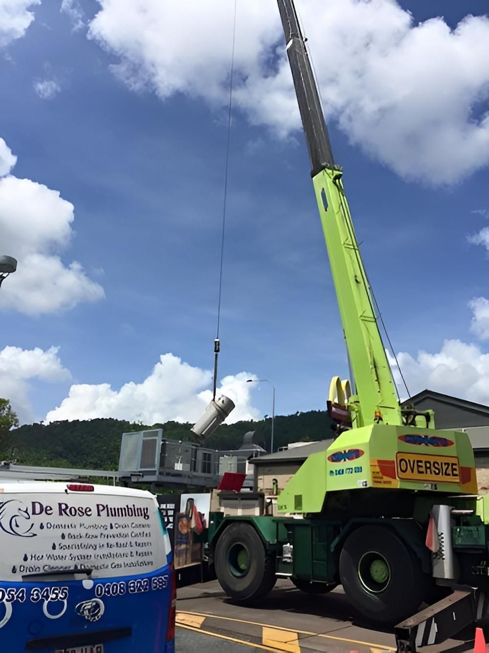 A Green Crane is Being Used to Lift a Large Object — De Rose Plumbing In Bayview Heights, QLD