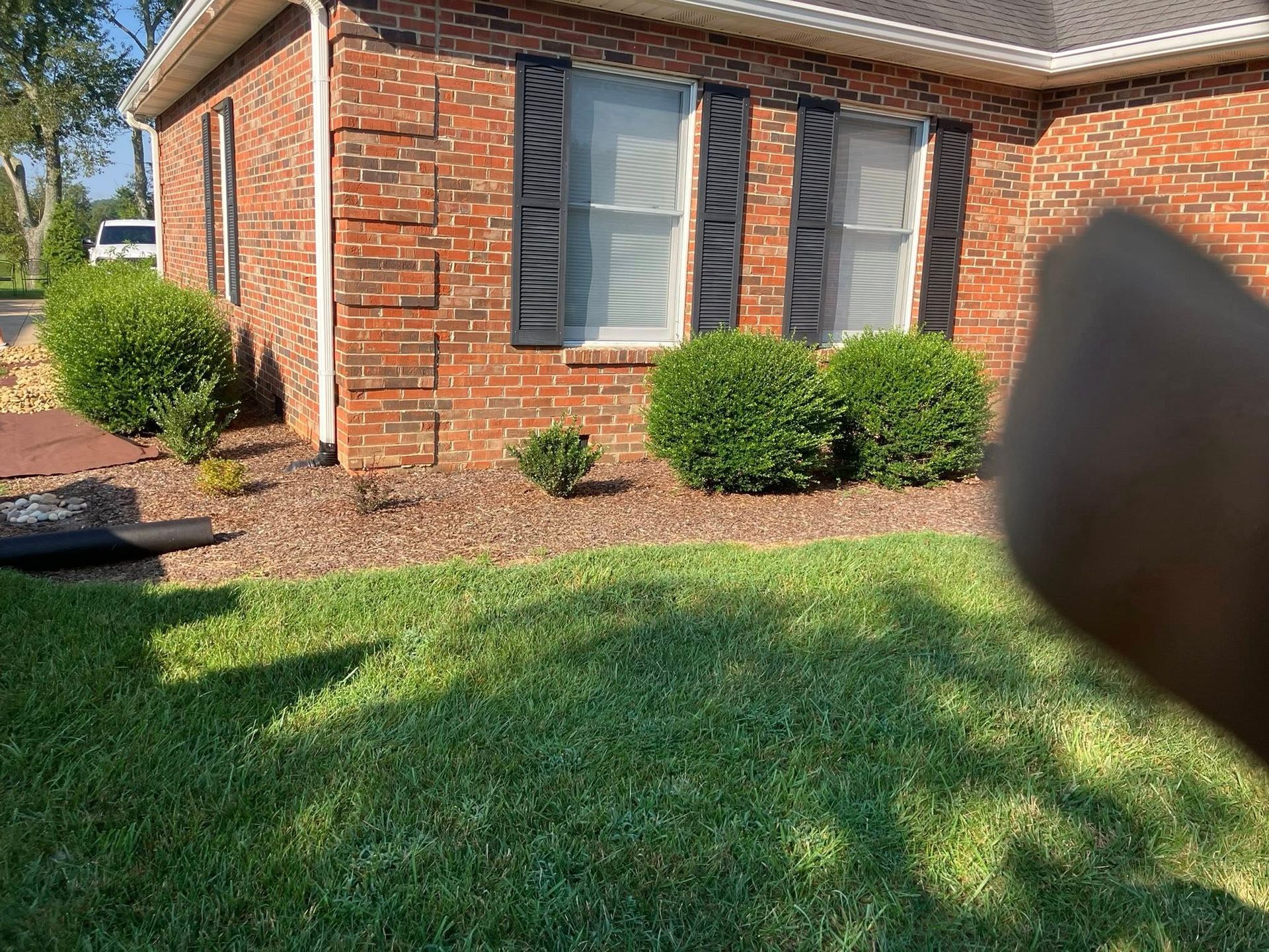 A person operating a mini-excavator digging a trench next to a house.