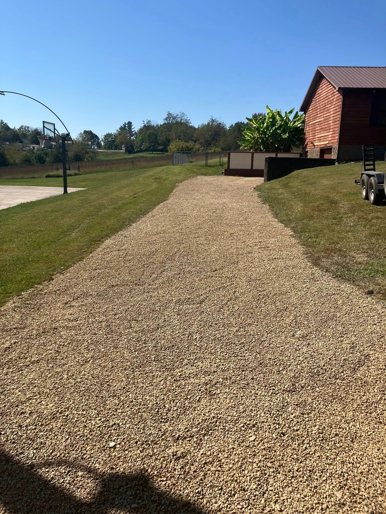 An excavator loads dirt into a dump truck on a construction site; trees in the background.