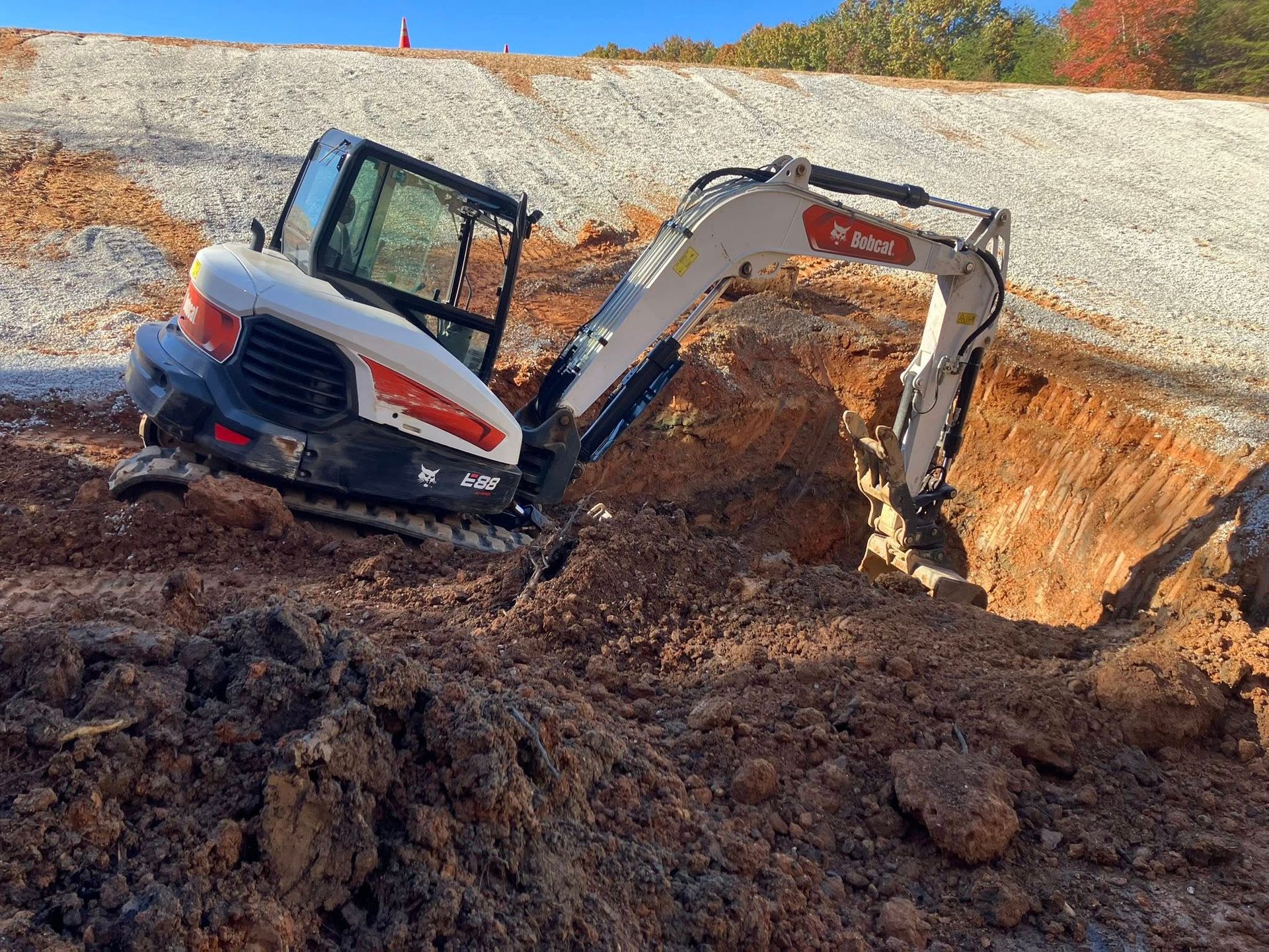 Construction site with excavator and workers around wooden forms.