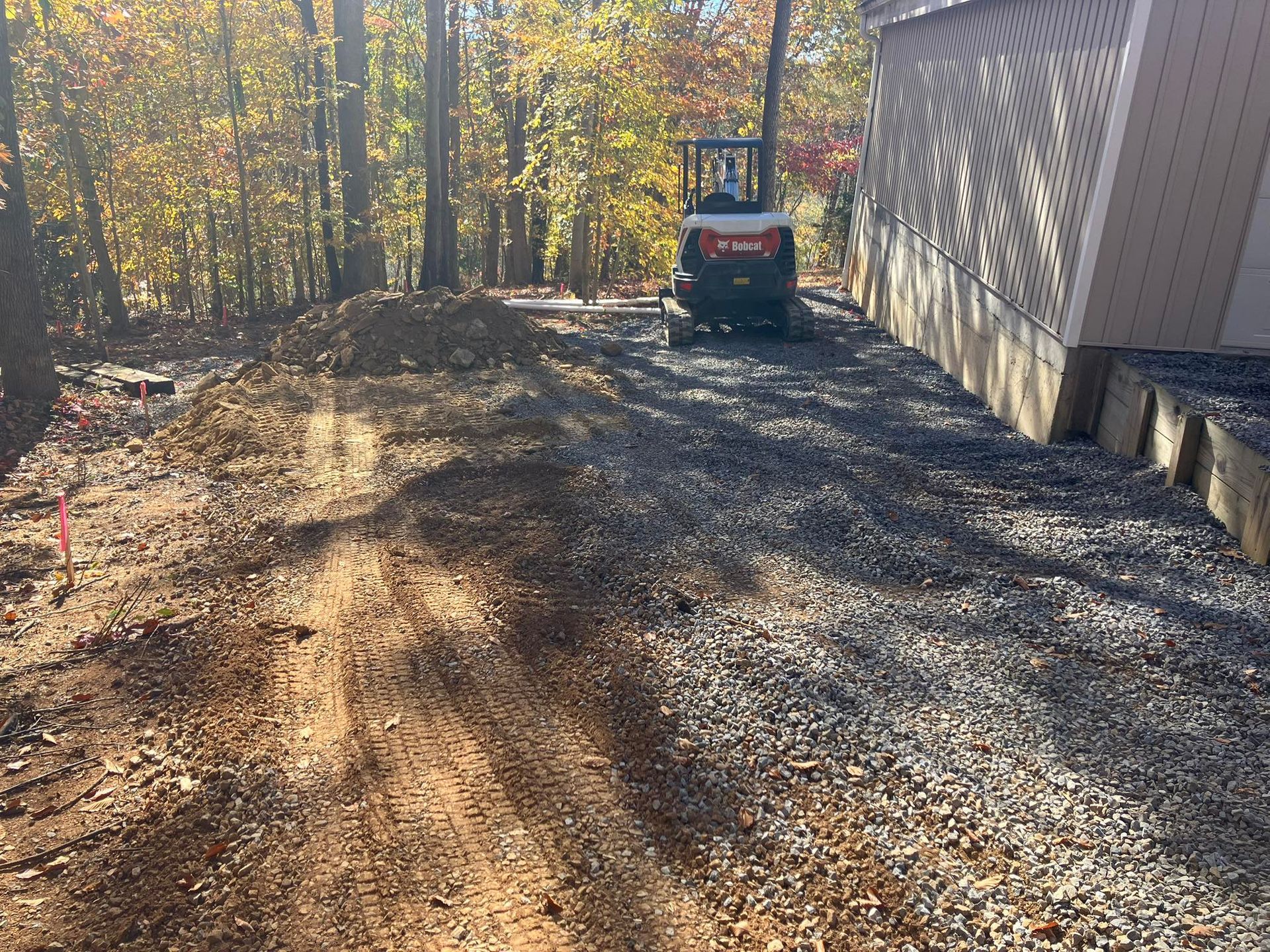 Yellow excavator clearing trees in a forest.