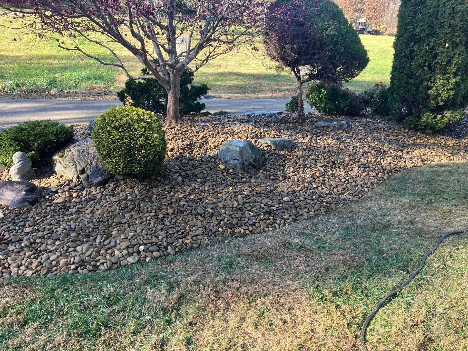 Man planting greenery in a garden bed near a street.