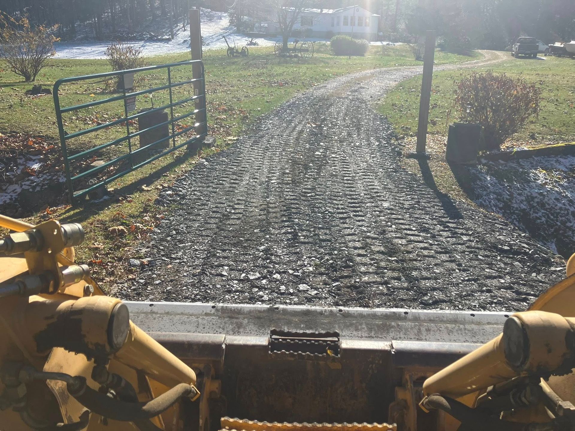Road roller compacting fresh asphalt on a roadway, another machine paving in the background. Cloudy sky.