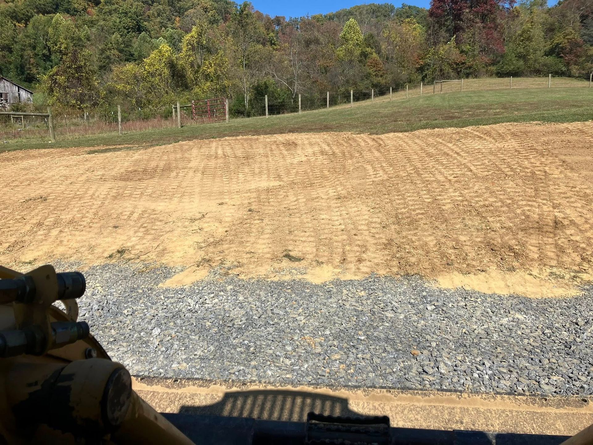 Log-filled tractor in a forest clearing; a worker stands on top under a blue sky.