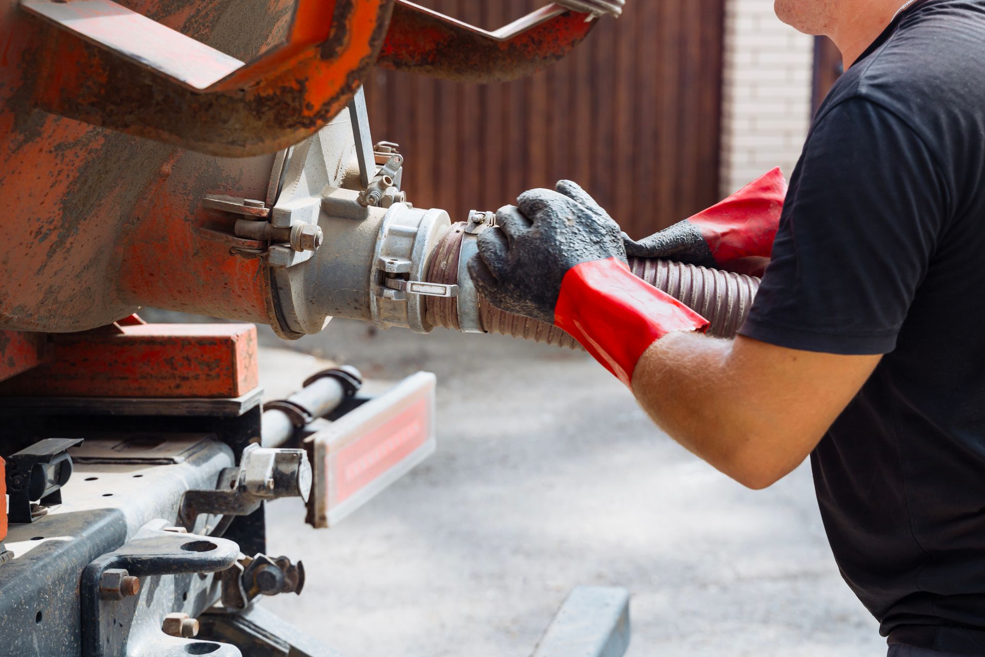 Man wearing gloves connecting a hose to a tank on a truck.