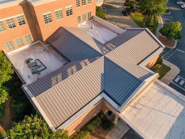 Overhead view of a building with a gray metal roof and brick exterior.