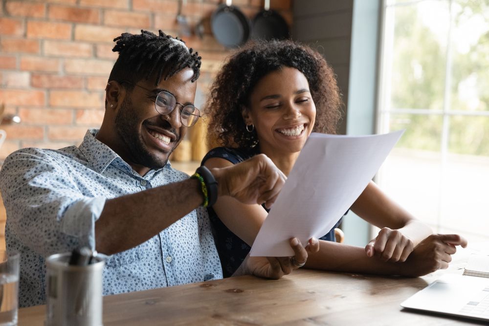 A man and a woman are sitting at a table looking at a piece of paper.