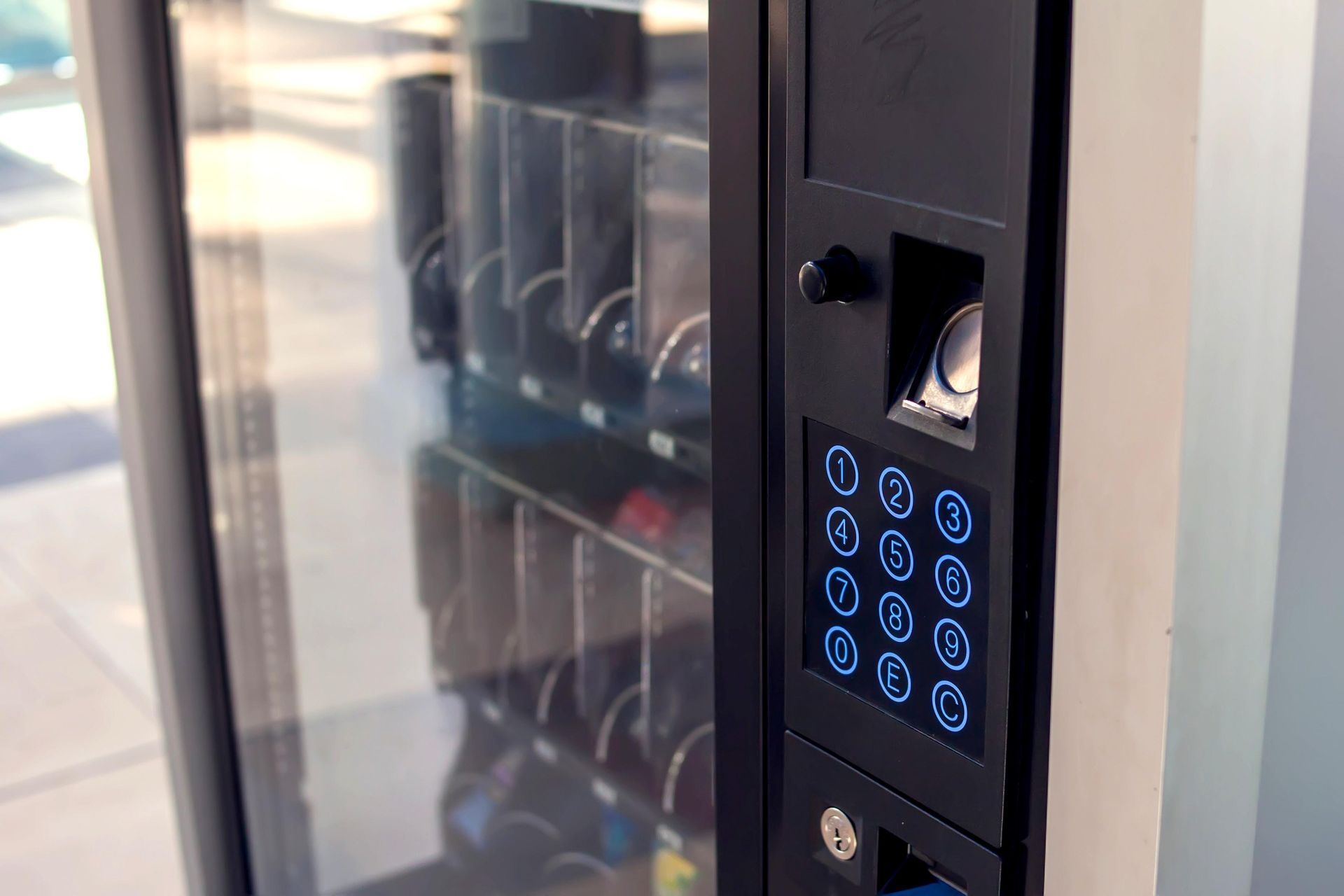 Vending machine with a keypad and card reader, with empty product shelves behind a glass door.
