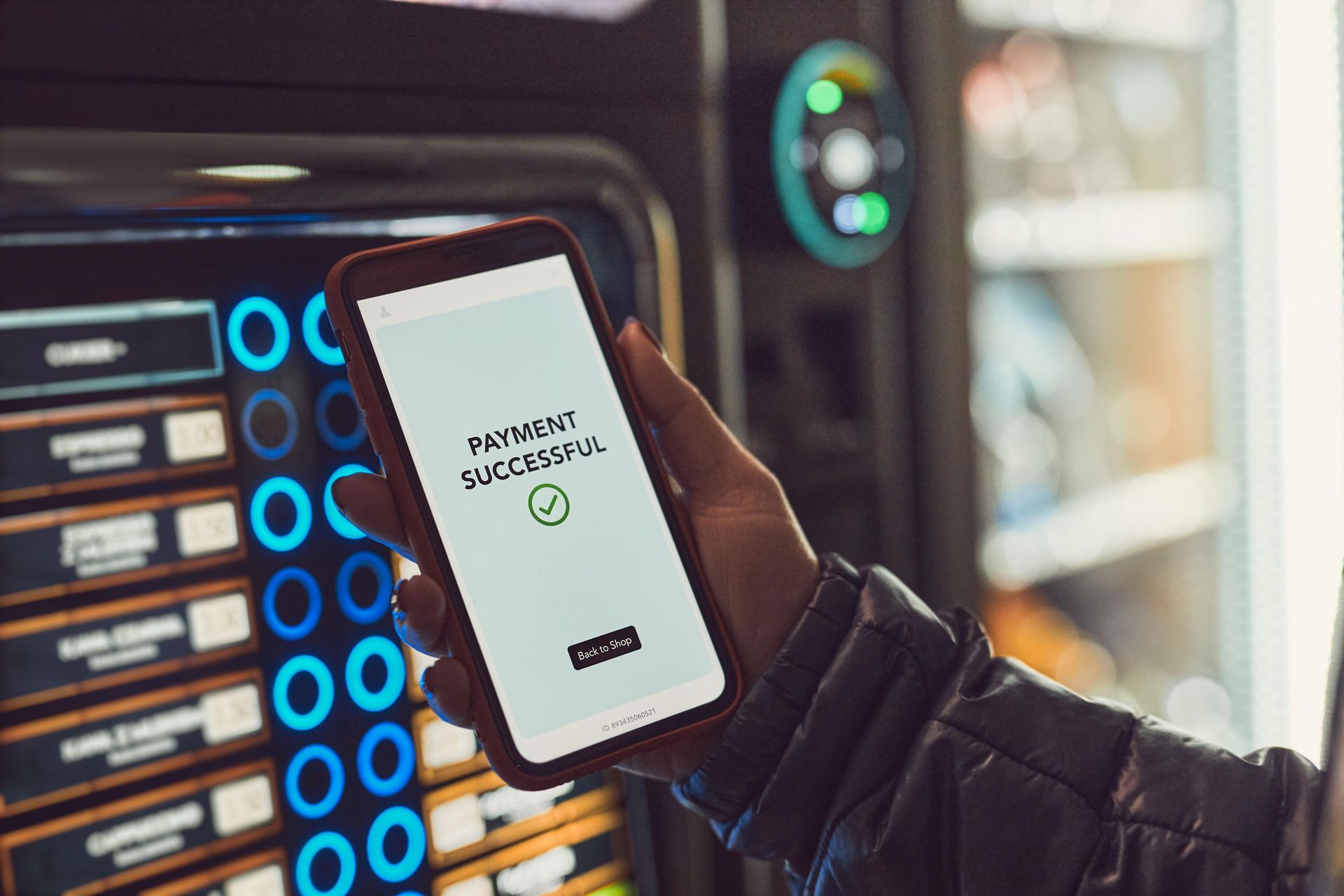 Person using a smartphone to pay at a vending machine with a payment confirmation displayed.