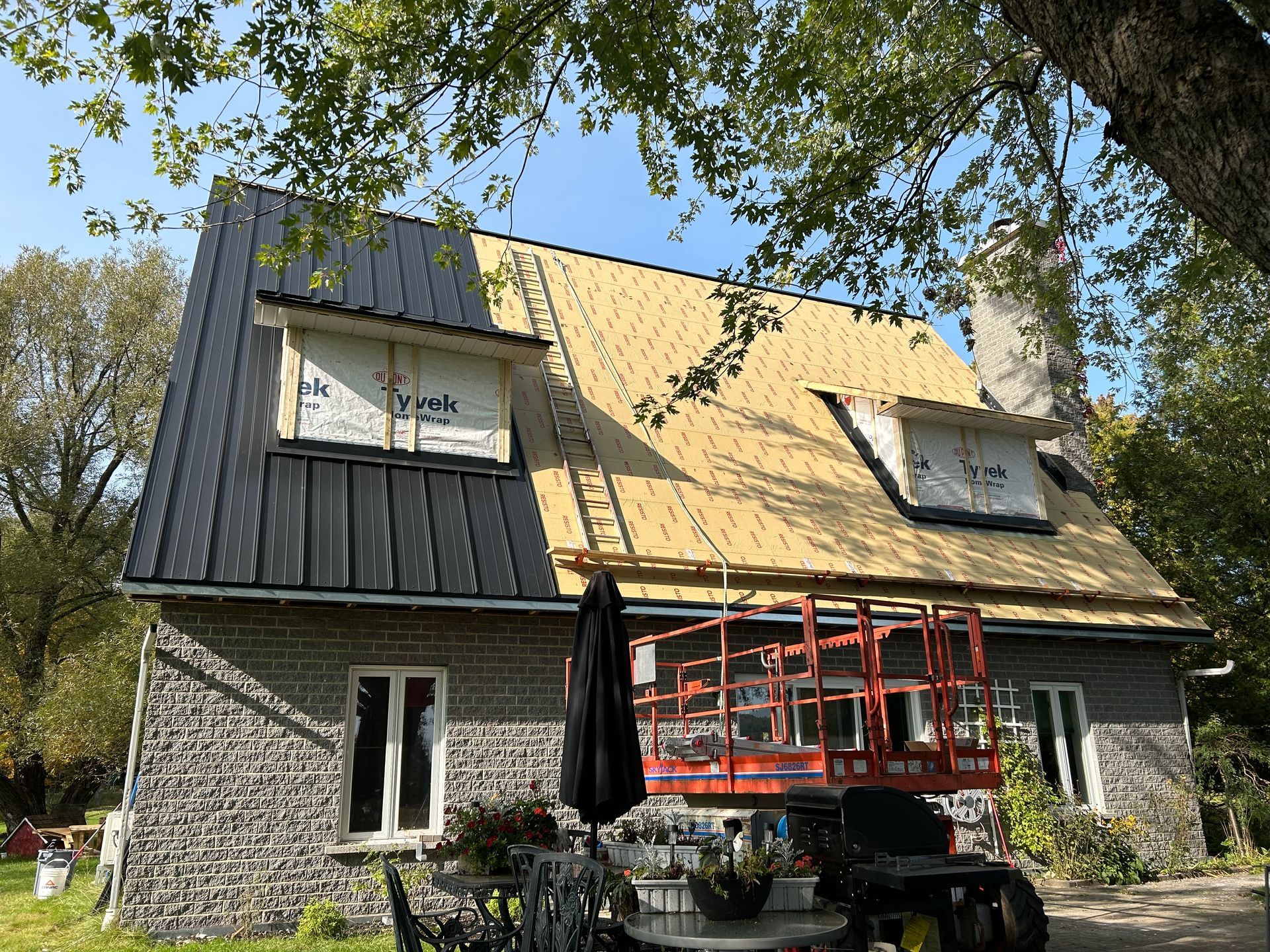 Toiture partiellement recouverte de métal noir. Nouvelles poutres apparentes. Ascenseur à l'avant.