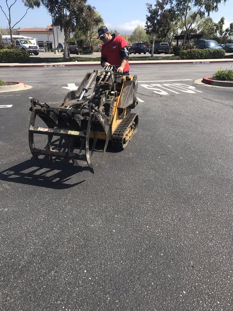 A man is driving a tractor in a parking lot.