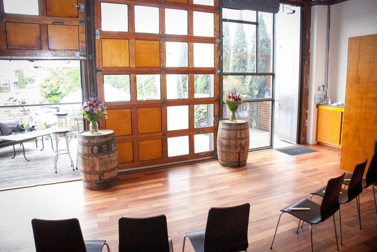 A room with chairs and barrels in front of a garage door.