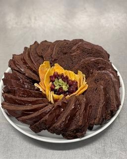 A white plate topped with a chocolate bundt cake and fruit.
