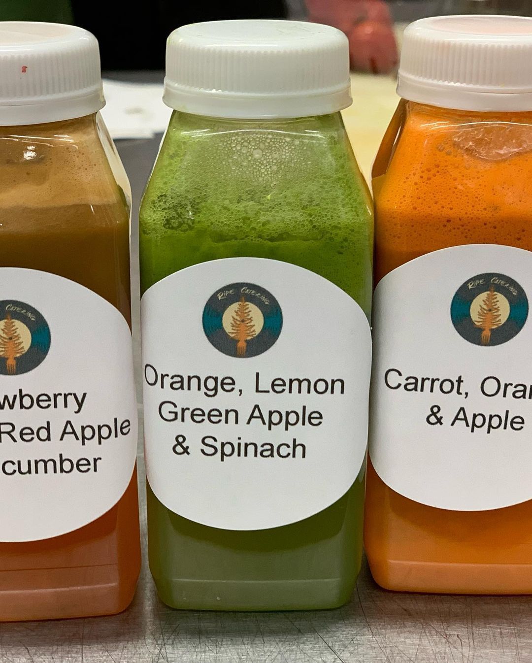 Three bottles of orange lemon green apple and spinach juice