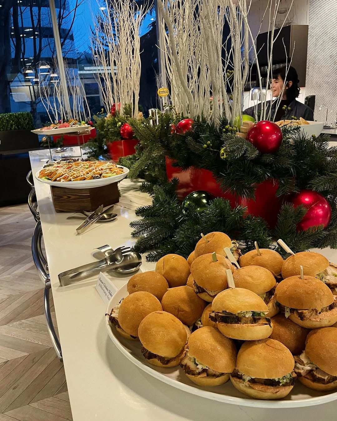 A plate of hamburgers on a table with a christmas wreath in the background.