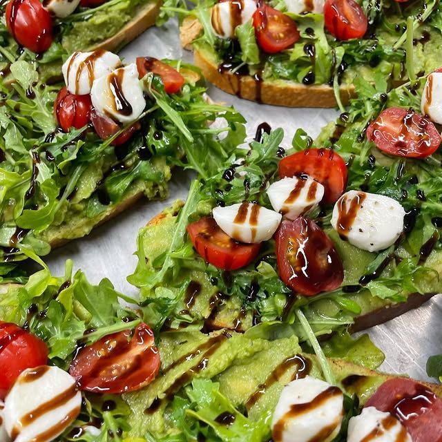 A close up of avocado toast with tomatoes and mozzarella on a table.