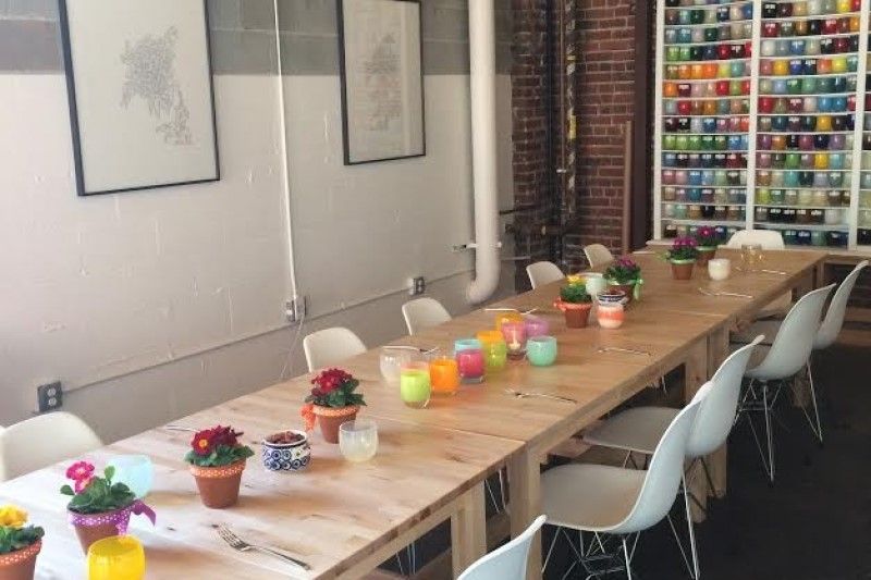 A long wooden table with potted plants and candles on it.