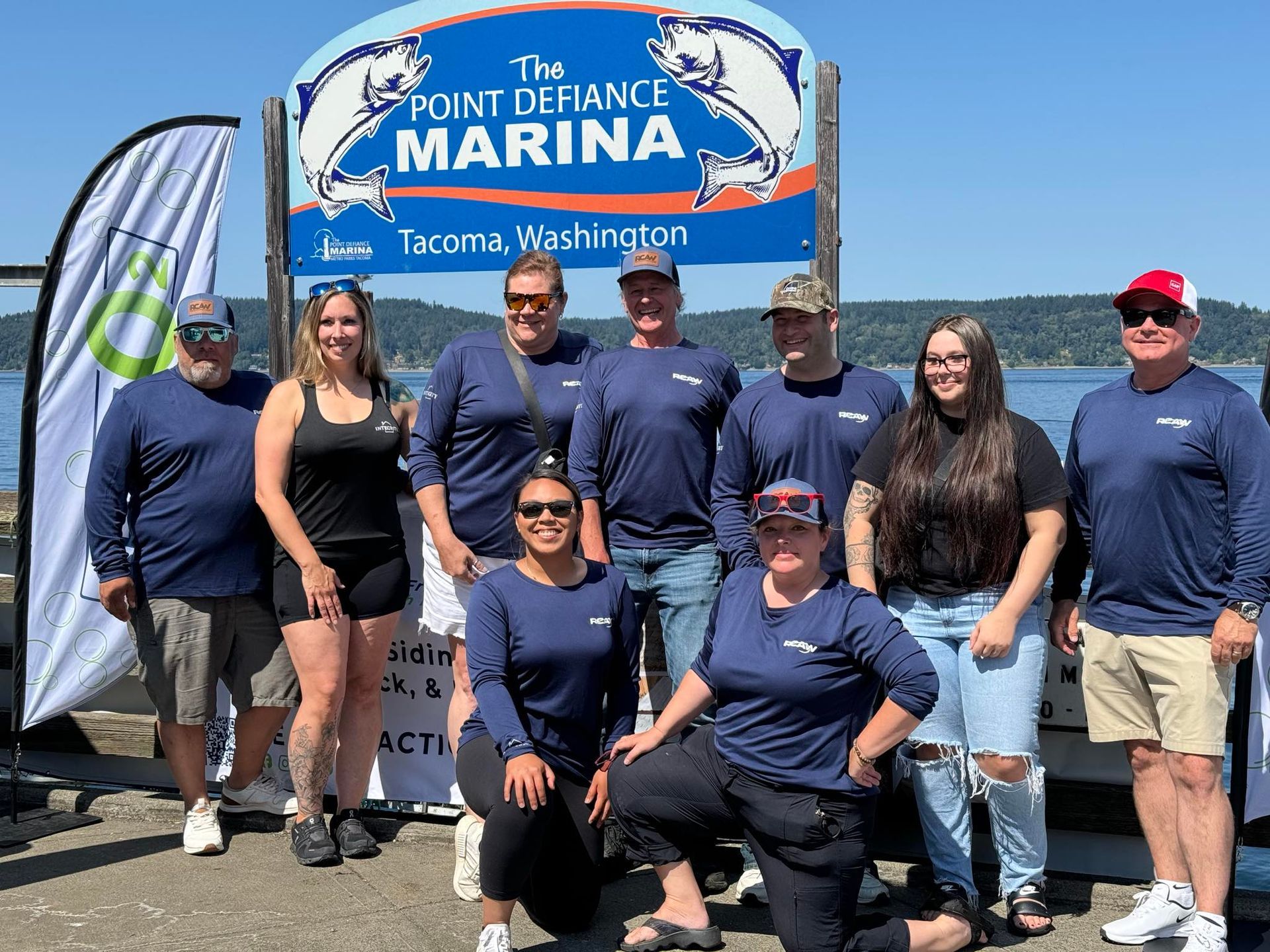 A group of people are posing for a picture in front of a marina sign.