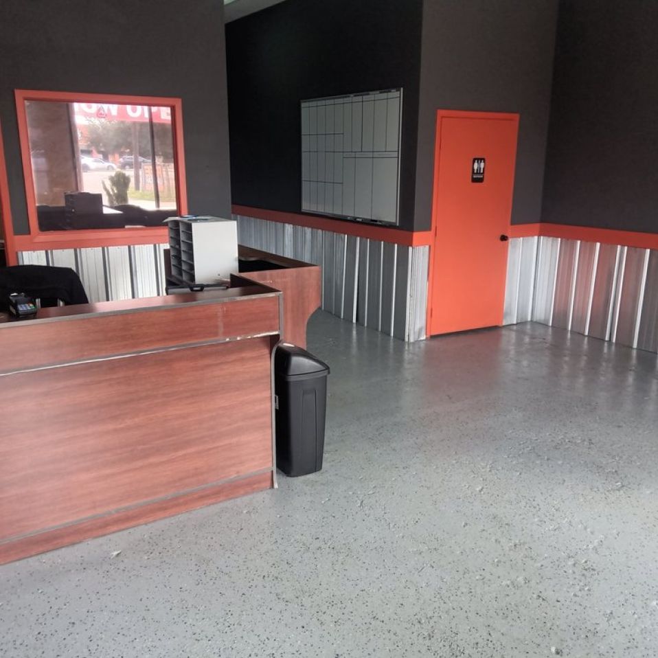 Empty office interior with wood desk, metal panel wainscoting, and orange door. | We Fix Cars