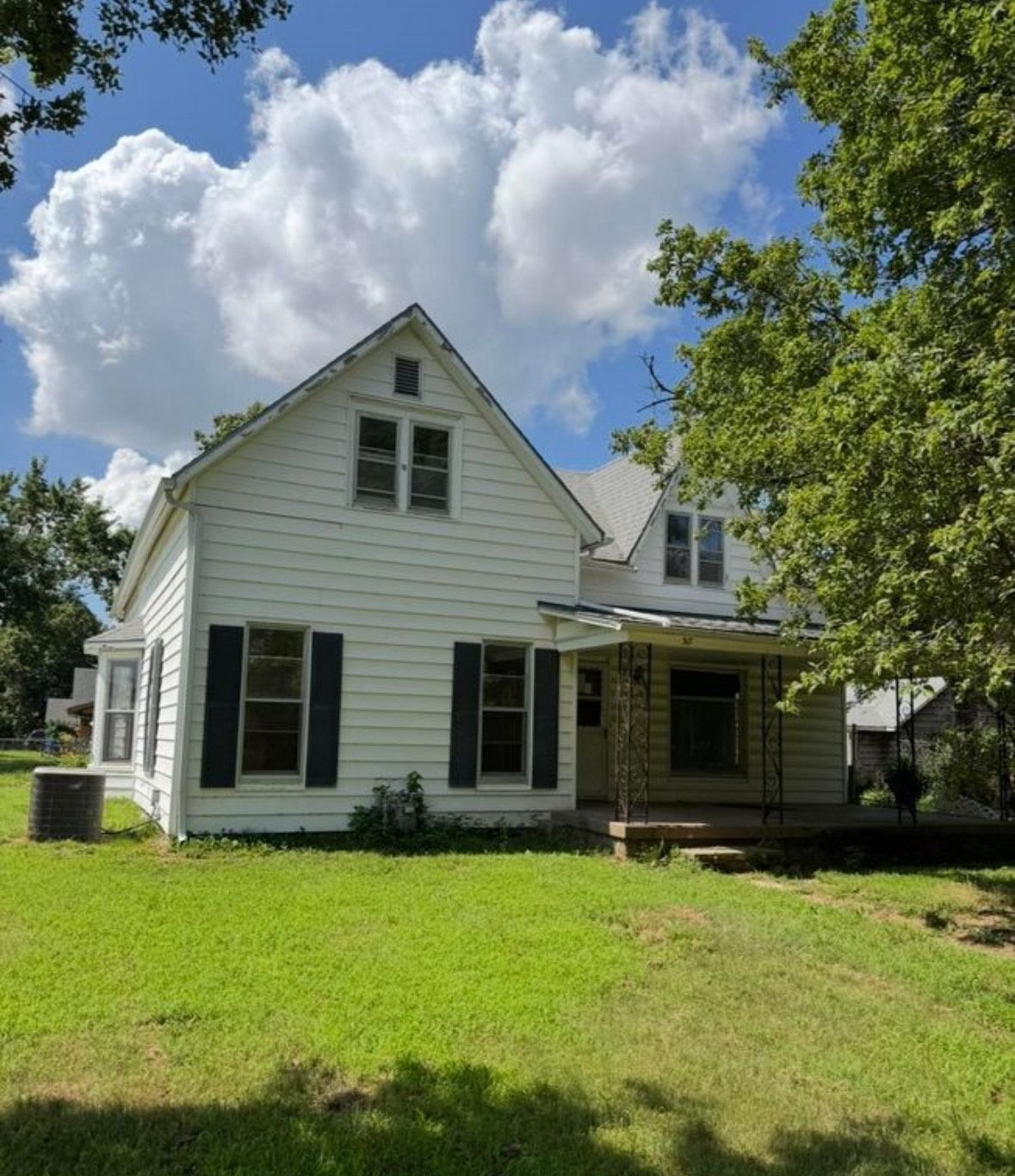 Hallway with hardwood floors, dark wood door, light walls, and decor including a rug and cactus.