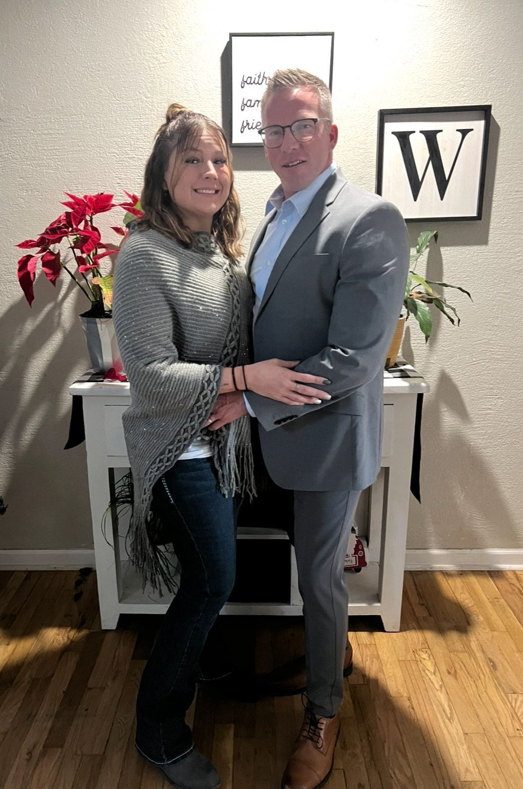 Couple looking at a new home, standing in an empty room, arms around each other.