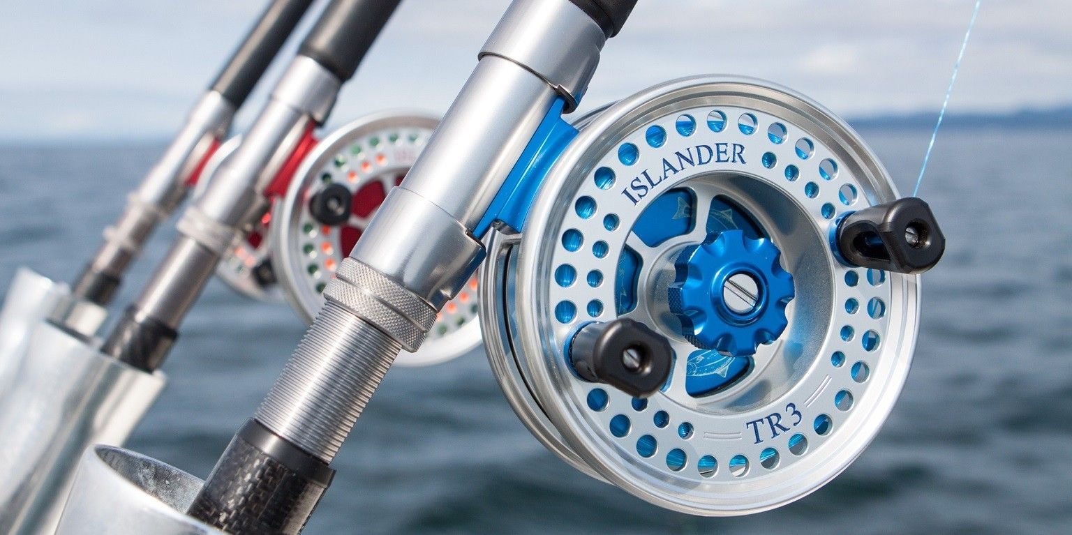 Fishing rods with reels on a boat; blue, red and silver.