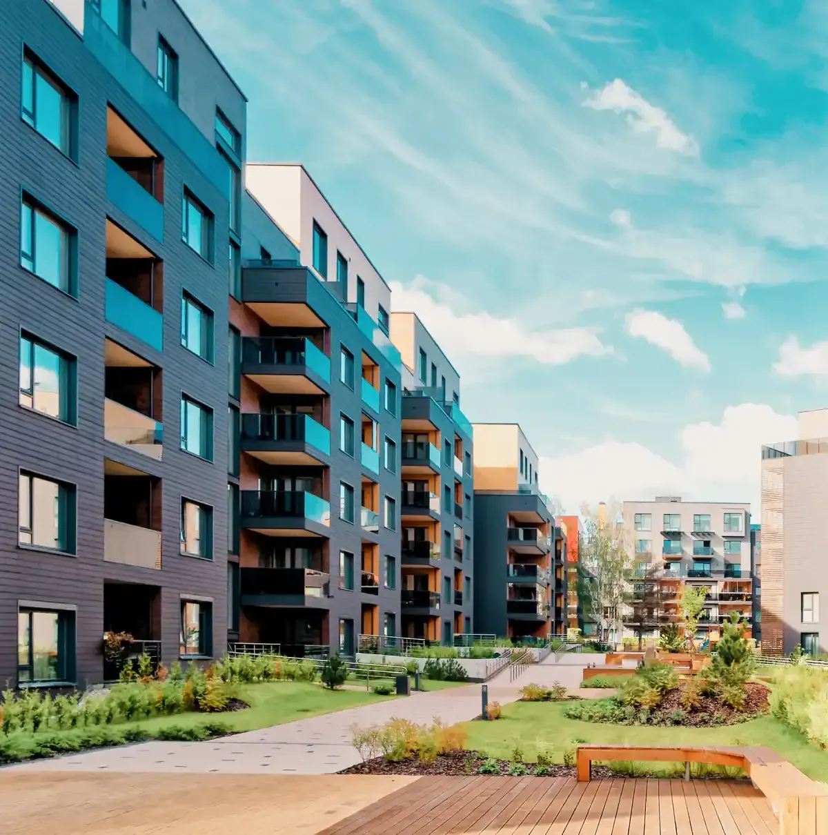 Modern apartment buildings lining a landscaped courtyard under a bright blue sky