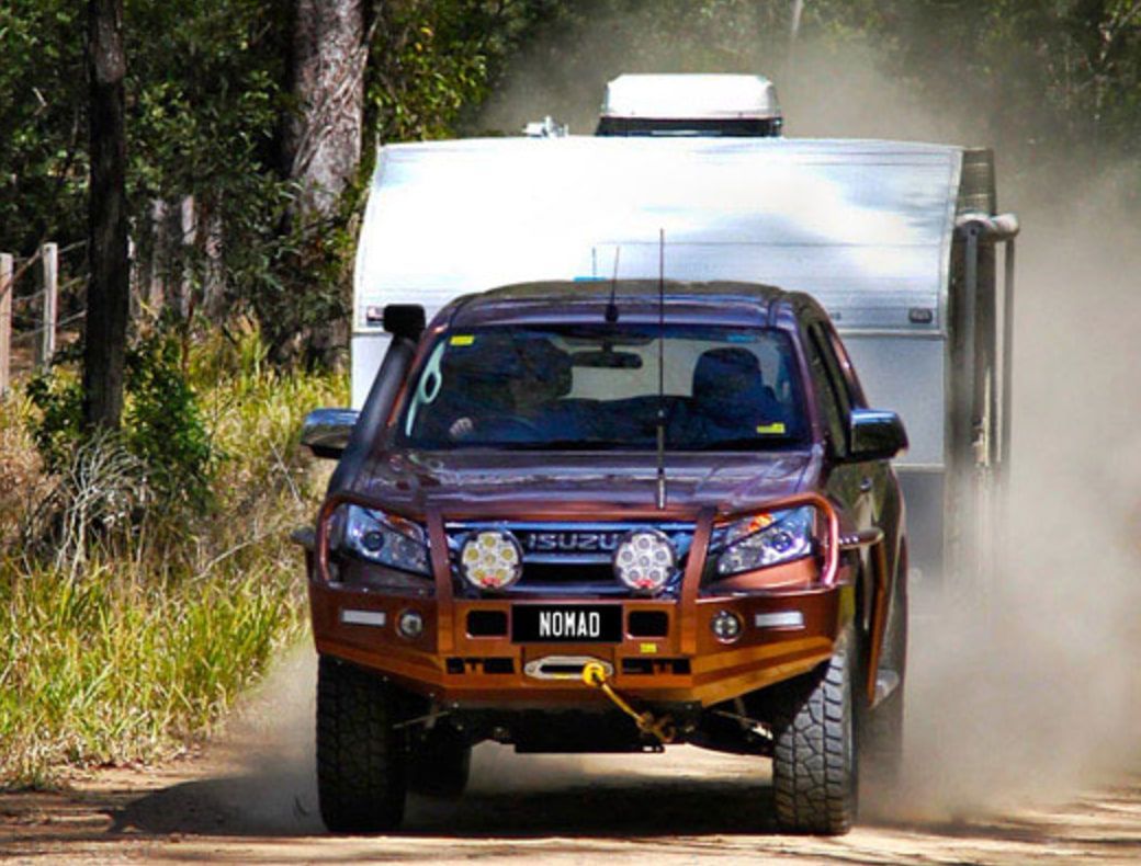 A Truck Is Driving Down A Dirt Road Next To A Trailer — Goulburn Automotive Centre In Goulburn, NSW