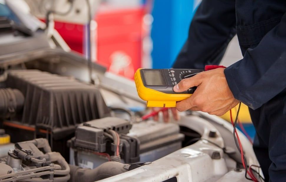 A Mechanic Is Using A Multimeter To Check The Voltage Of A Car Battery — Goulburn Automotive Centre In Goulburn, NSW
