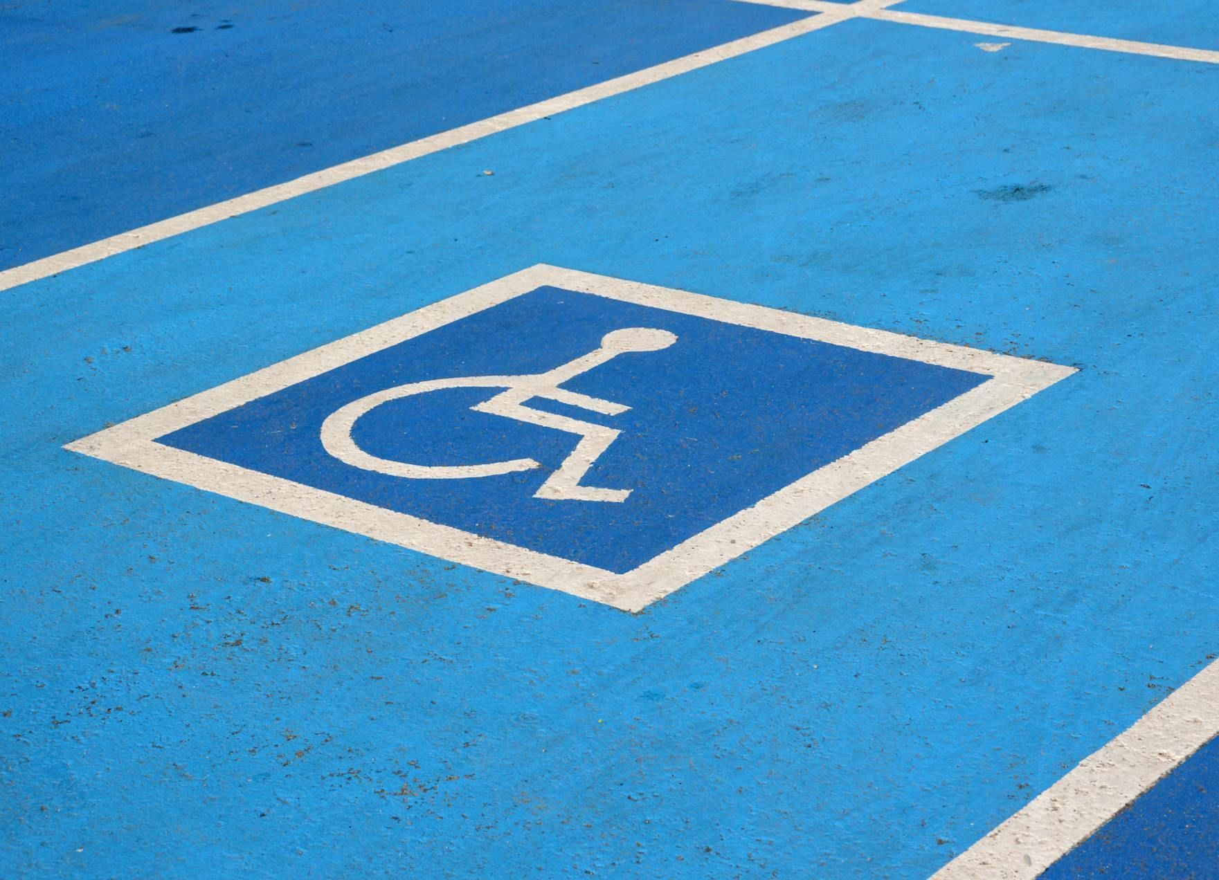 A blue parking lot with a handicapped sign painted on it